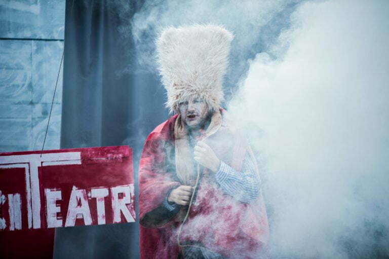 Pictures from the play,,Pinocchio" A figure in a red coat and large fur hat emerges from the smoke. On the back you can see a fragment of the inscription - Theatre.