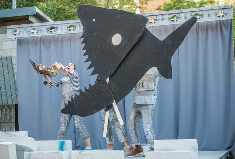 Zdjęcie ze spektak;u Pinokio. Drewniana lalka Pinokia wpada do paszczy wielkiego czarnego rekina.