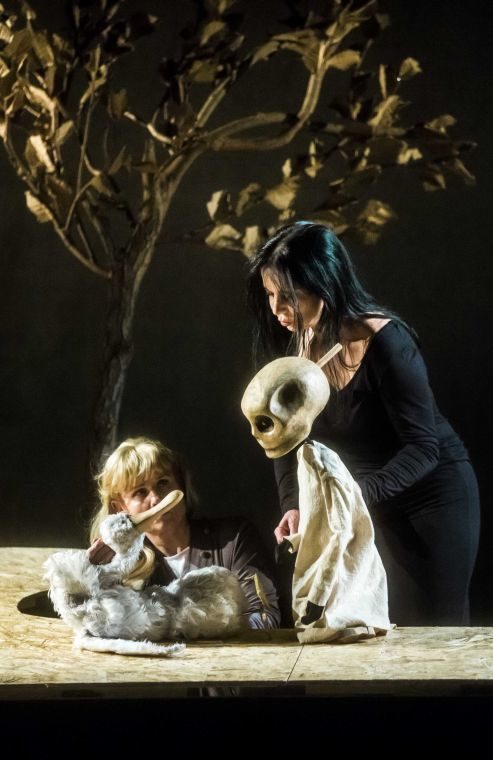 Zdjęcie ze spektaklu Gęś, Śmierć i Tulipan. Animowana przez aktorkę lalka Gęsi spogląda na stojącą nad nią Śmierć. W tle widać drzewo.