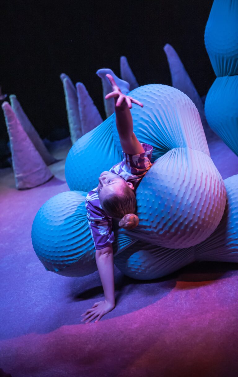 The actress is lying on her back, with one hand stretched out in front of her, surrounded by huge connected balls that play the role of intestines in the show. A performance for the youngest children from 0 to 3 years, showing the workings of internal organs. In this case, the work of the intestine